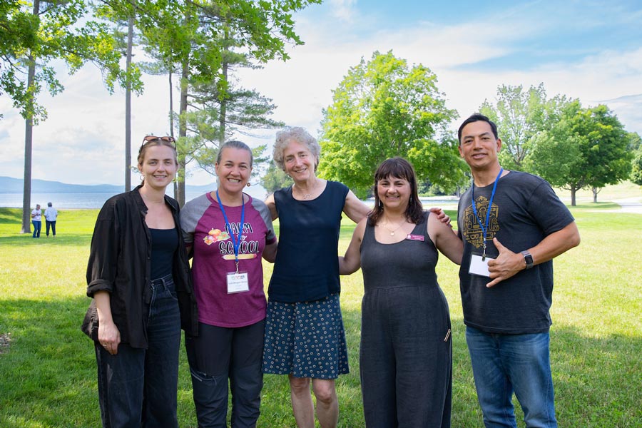 A group of five people smiling outdoors on the Coach Barn lawn.