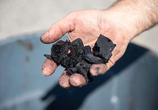 close up of black biochar in someone's hand
